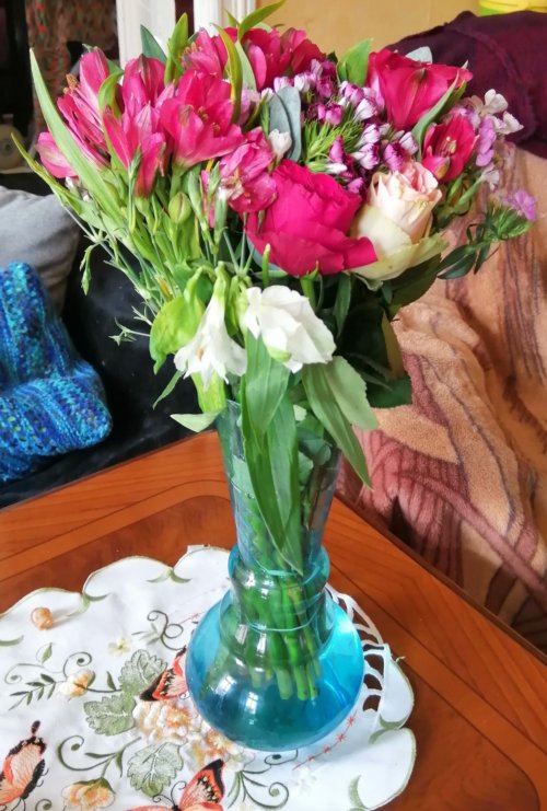 Eine Vase mit Blumen die auf einem Tisch steht.